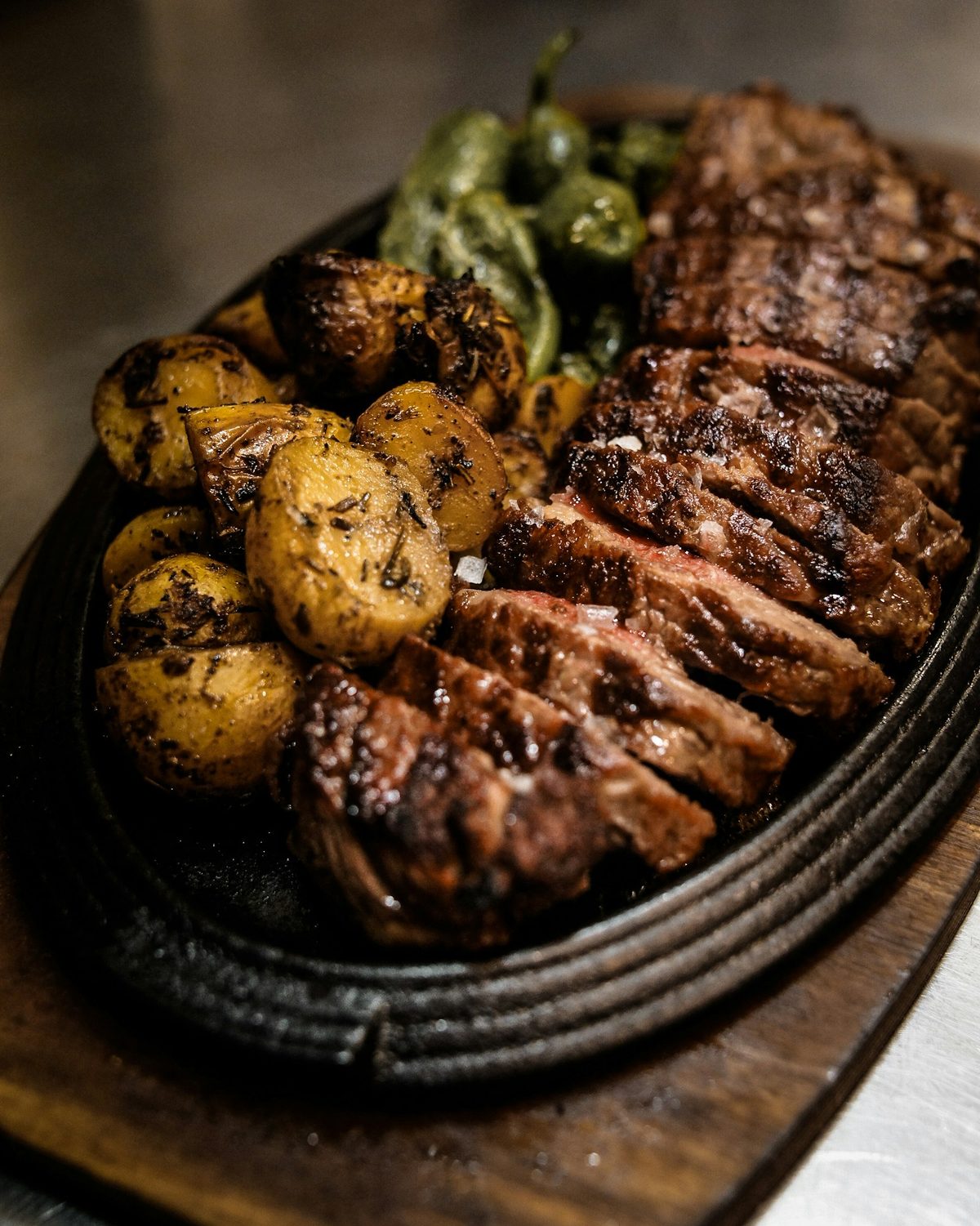 Angeschnittenes Steak vom Grill mit geröstetem Gemüse auf einem dunklen Teller